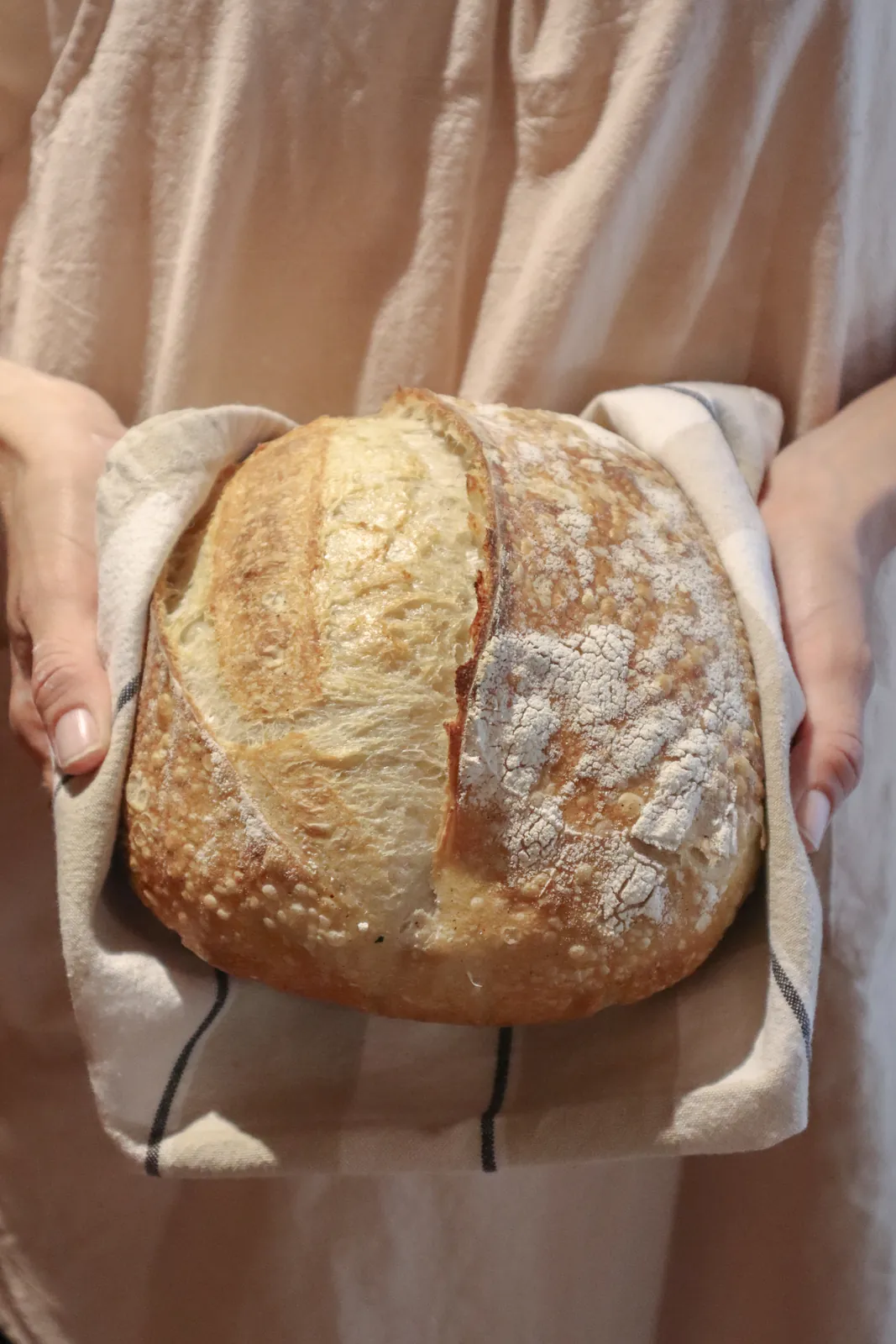 Manos sosteniendo una hogaza de masa madre recién horneada